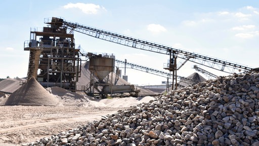 Kiesgewinnungsanlage mit Kieshaufen im Vordergrund