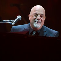 Billy Joel sitzt an einem schwarzen Flügel während seiner 100. Performace im Madison Square Garden in New York City, USA.