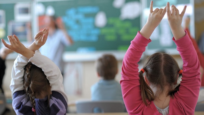 Zwei Schülerinnen melden sich während des Unterrichts in einem Klassenzimmer