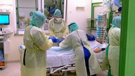 Ärztinnen und Ärtzte versorgen auf einer Intensivstation eine Patientin.