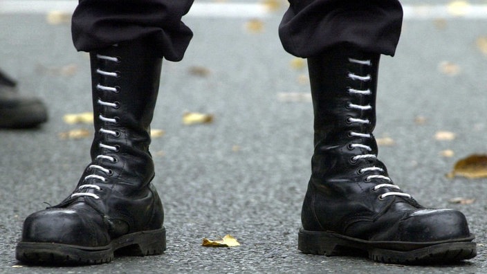 Schwarze Springersteifel mit weißen Schnürsenkeln auf Asphalt