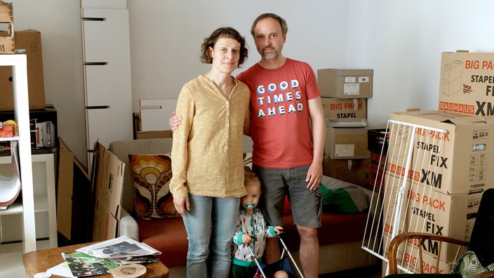Eine Familie steht inmitten von Umzugskartons