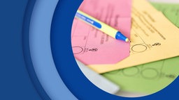 Nahaufnahme von verschiedenen Wahlscheinen und einem Stift, der darauf liegt.