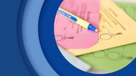Nahaufnahme von verschiedenen Wahlscheinen und einem Stift, der darauf liegt.