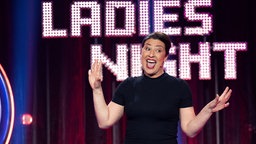Eva Eiselt steht mit angehobenen Armen auf der Bühne - im Hintergrund ist der Schriftzug "Ladies Night" zu sehen