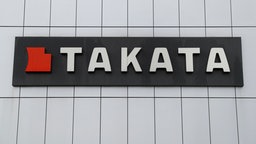 Das Bild zeigt das Logo von "Takata" an einer Gebäudewand. 
