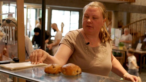 Eine Frau steht an der Essensausgabe einer Tafel