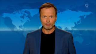 Der Tagesthemen-Kommentar von Georg Restle blickt in die Kamera vor dem Hintergrund des Tagesthemen-Studios.