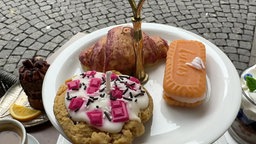 Das Bild zeigt einen Teller mit den Foodkerzen, darunter ein Keks, ein Croissant und ein Cookie. 