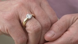 Das Bild zeigt die Hand einer älteren Person mit einem Diamantenring.