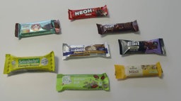 Das Bild zeigt verschiedene Snack Riegel im Test.
