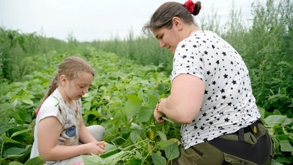 Das Bild zeigt Mutter Cindy mit eines ihrer Kinder in einem Gemüsefeld.