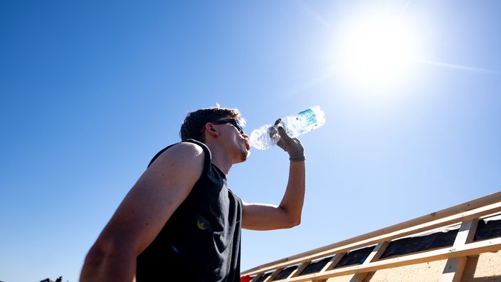 Ein Dachdecker der Firma «Dachdecker Ditscheid» trinkt Wasser unter der sengenden Sonne bei über 30 Grad auf dem Dach eines Hauses im Rhein-Sieg-Kreis.