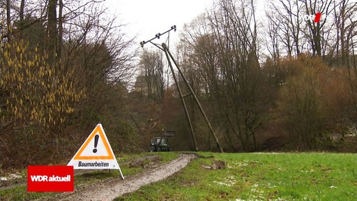 Ein Warnschild vor einem Mast, der droht umzustürzen