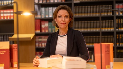 Anna Planken an einem Tisch, vor ihr liegen verschiedene Bücher.