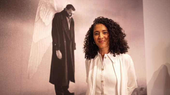 Siham El-Maimouni vor dem "Der Himmel über Berlin"-Filmcover mit Bruno Ganz