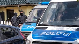 Vermummte Polizisten und Polizeiautos bei Razzia in Brandenburg