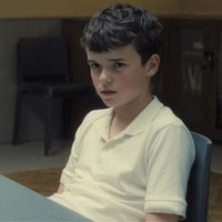 Szene aus der britischen Netflix-Serie "Adolescence": Junge in weißem T-Shirt sitzt an einem Tisch