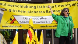 Eine Rednerin steht vor einem Plakat, auf dem "Atommüllverschiebung keine Entsorgung" steht