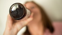 Eine Jugendliche trinkt aus einer Bierflasche
