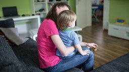 Mutter sitzt mit ihrem Kind auf der Couch 