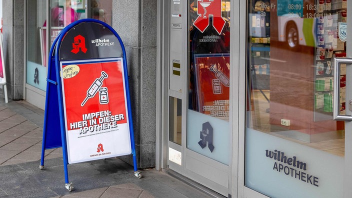 Eine Apotheke mit einem Aufsteller vor dem Eingang, der auf die Möglichkeit einer Grippeschutzimpfung hinweist