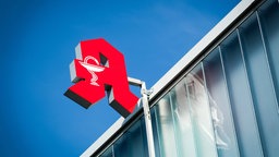Ein rotes Apothekenschild an einer Hausfassade