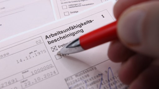 Jemand setzt ein Kreuz bei der Arbeitsunfähigkeitsbescheinigung