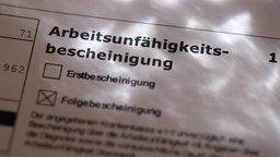 Eine Arbeitsunfähigkeitsbescheinigung vom Hausarzt mit dem Kreuz bei Folgebescheinigung 