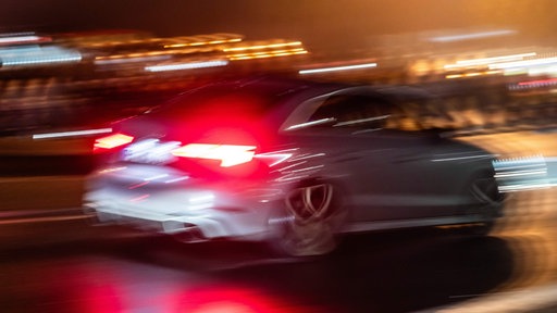 Ein Auto fährt bei Dunkelheit über eine Straße 