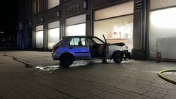 Kaputter PKW vor eingefahrener Schaufensterscheibe