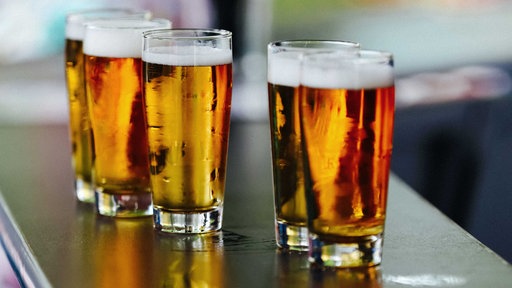 Fünf Gläser gefüllt mit Bier stehen auf einer Theke.