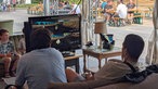 Zwei Junge Männer zocken Mario Kart auf einem Bildschirm