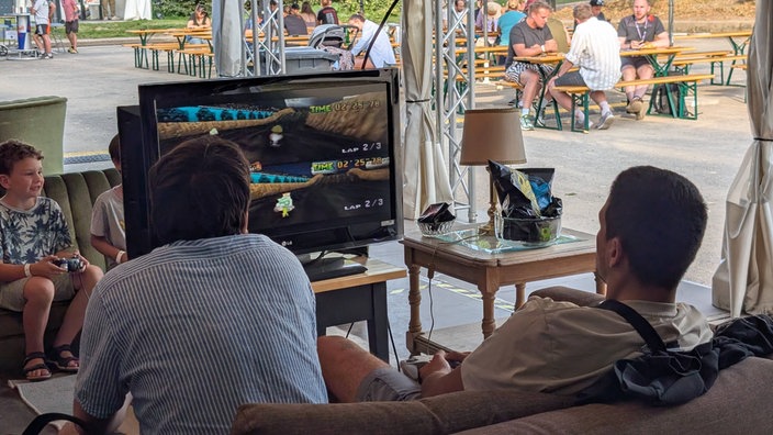Zwei Junge Männer zocken Mario Kart auf einem Bildschirm