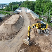 Ein Bagger steht vor einer Brücken-Baustelle.