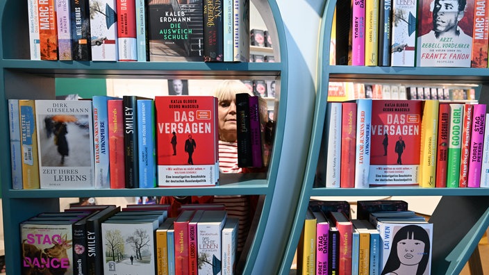 Frau ordnet Bücher in einem Regal