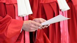 Jemand vom Bundesverfassungsgericht hält ein Papier in der Hand