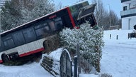 Ein Bus hängt in einer tiefen Einfahrt, nachdem er vor einer Kurve abrutschte 