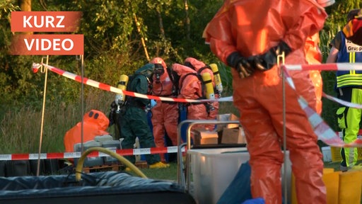 Spezielle Einheit der Feuerwehr in Schutzanzügen betrachtet gefundene Fässer 
