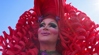 Bunt geschminkte und schrill gekleidete Teilnehmer*in bei der Parade des CSD in Köln