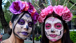 Zwei Frauen haben ihre Gesichter in Anlehnung an die "Catrina" geschminkt
