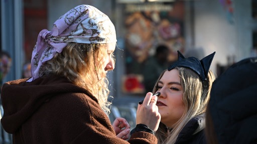 Zwei junge Frauen treffen letzte Vorbereitungen was das Make Up angeht am 11.11.