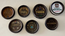 Sieben Holzfässer mit Symbolen der Dortmunder Biere an der Wand im Innenhof. 