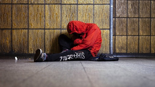 Eine Person unter dem Einfluss von Drogen sitzt in einer U-Bahn-Haltestelle in Köln