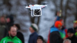 Eine mit einer Kamera bestückte Drohne fliegt über Zuschauer