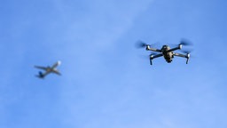 Eine Drohne fliegt vor einem startenden Flugzeug in der Nähe des Flughafens Leipzig/Halle