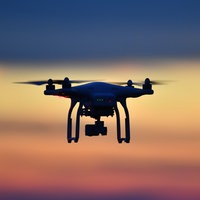  Eine Drohne fliegt bei Sonnenuntergang über eine Wiese