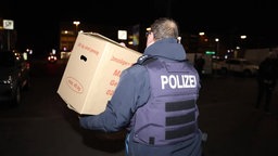 Ein Polizeibeamter trägt einen Karton aus der Sparkassen-Filiale in Gelsenkirchen