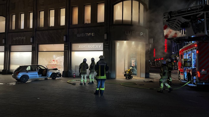 Feuerwehrkräfte beim Einsatz, nachdem ein Auto in ein Schaufenster gefahren ist