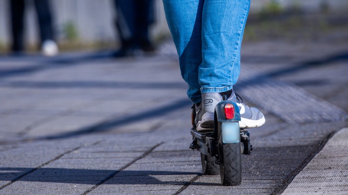 Füße und Beine eines Fahrers auf einem E-Scooter